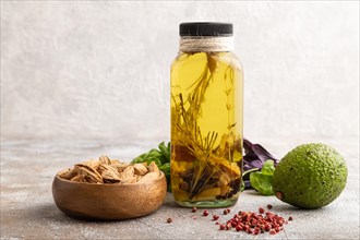 Sunflower oil in a glass jar with various herbs and spices, sesame, rosemary, avocado, basil,