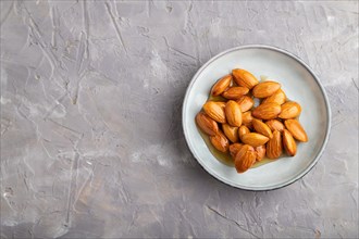 Almonds with honey on gray concrete background. top view, flat lay, close up, copy space
