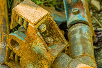 Closeup of rusted metal industrial machine parts discarded and laying on the ground