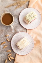 Roll biscuit cake with cream cheese and jam, cup of coffee on brown concrete background and orange