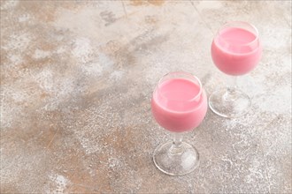 Sweet strawberry liqueur in glass on a gray concrete background. Side view, copy space