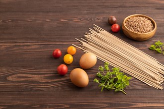 Japanese buckwheat soba noodles with tomato, eggs, spices, herbs on brown wooden background. Side