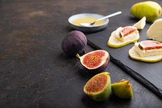 Summer appetizer with pear, cottage cheese, figs and honey on slate board on a black concrete