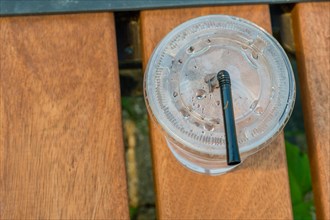 Single use plastic cup and straw left on wooden bench in public park on sunny day in Sintanjin,