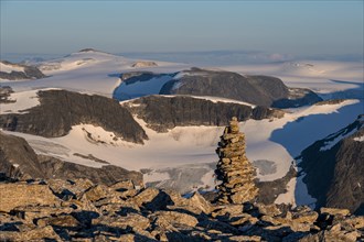Cairn at the summit of Skala, warm light at sunset, summit and glacier Jostedalsbreen in the