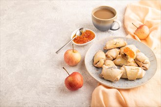 Homemade sweet cookie with apple jam and cup of coffee on gray concrete background and orange linen