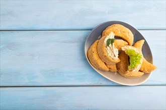Homemade salted crescent-shaped cheese cookies on blue wooden background. top view, flat lay, copy
