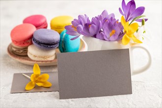 Gray paper business card mockup with spring snowdrop crocus flowers and multicolored macaroons on