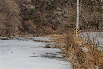 Winter scene of water in river with rocky shoreline frozen in South Korea