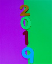 The numbers 2019 made of felt of different colors photographed on green and maroon background