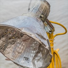 Metal work light with yellow electrical cord and a blurred background