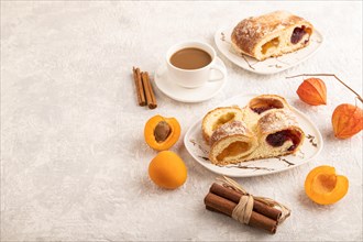 Homemade sweet bun with apricot jam and cup of coffee on gray concrete background. side view, copy