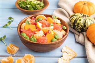 Vegetarian fruit salad of pumpkin, tangerine, pomegranate, grapefruit, sunflower microgreen sprouts