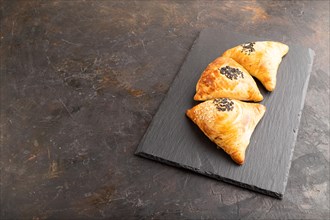 Homemade asian pastry samosa on black concrete background. side view, copy space
