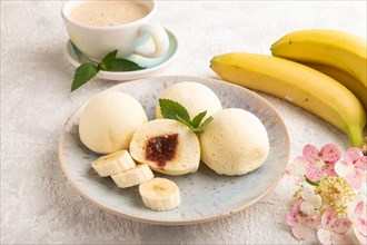 Japanese rice sweet buns mochi filled with jam and cup of coffee on a gray concrete background.