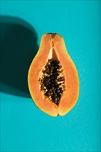 Ripe cut papaya on blue pastel background. Top view, flat lay, close up, hard light. Tropical,
