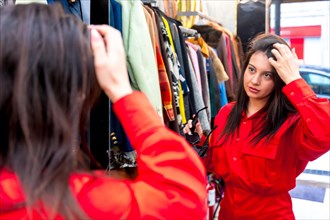 Woman looking in the mirror while shopping in a second hand store