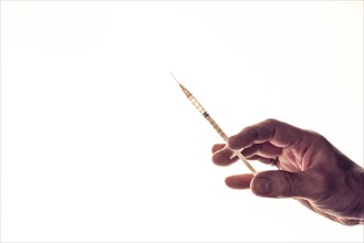 Concept image vaccination, male hand with medical syringe in front of white background, studio