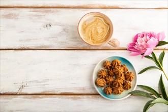 Homemade soft caramel fudge candies on blue plate and cup of coffee on white wooden background,