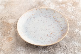 Empty blue and gold ceramic plate on brown concrete background. Side view, copy space