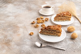 Walnut and hazelnut cake with caramel cream, cup of coffee on brown concrete background. side view,