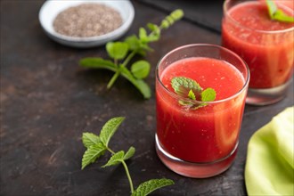 Watermelon juice with chia seeds and mint in glass on a black concrete background with green