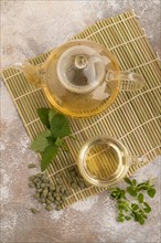 Green oolong tea with herbs in glass on brown concrete background. Healthy drink concept. Top view,