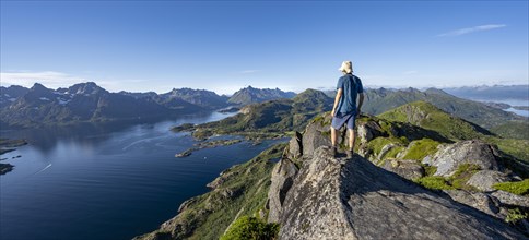 Mountaineer on the summit of Dronningsvarden or Stortinden, mountains and fjord Raftsund,