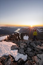 View of mountains and fjord Faleidfjorden, sun star at sunset, mountaineer at the summit of Skala,