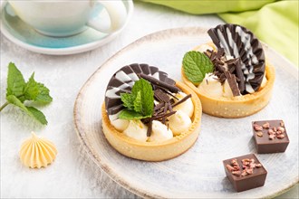 Sweet tartlets with chocolate and cheese cream with cup of coffee on a gray concrete background and