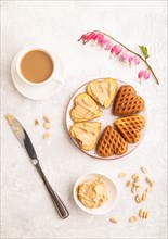 Homemade waffle with peanut butter and cup of coffee on a gray concrete background. top view, flat