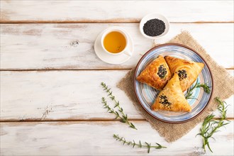Homemade asian pastry samosa, cup of green tea on white wooden background and linen textile. top