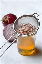 Honey in a jar and chopped onion as ingredients for cough syrup, sieve