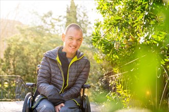 Portrait with copy space and focus on a cheerful disabled man using wheelchair in a park
