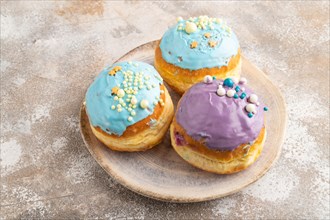 Purple and blue glazed donut on brown concrete background. side view, close up. Breakfast, morning,