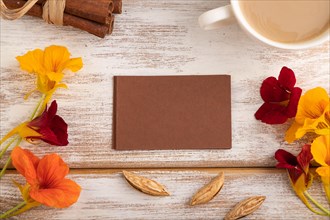 Brown paper business card mockup with orange nasturtium flower and cup of coffee on white wooden