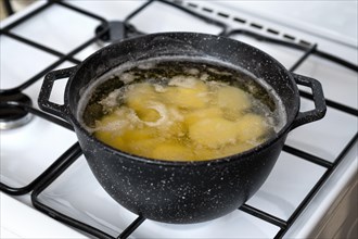Cooking halved potato in a pot with boiling water on a gas stove