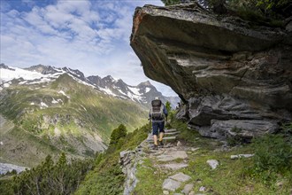 Mountaineer on a hiking trail under a rocky outcrop in a picturesque mountain landscape, Berliner