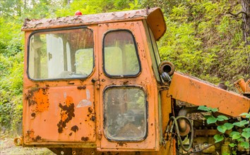 Left side cab section of old, rusting, broken down bulldozer abandoned in wilderness