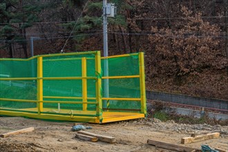 Yellow crane lifting platform at mountainside construction site