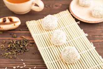 Japanese rice sweet buns mochi filled with pandan and coconut jam and cup of green tea on brown