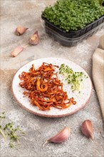 Fried Cordyceps militaris mushrooms on brown concrete background with microgreen, herbs and spices.