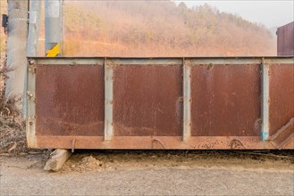 Old iron truck bed on side of country road on hazy morning with field and mountain in background