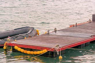 Black rubber dinghy tied to red floating dock in Jeju, South Korea, Asia