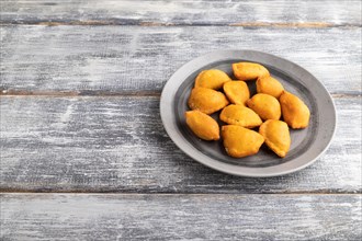 Fried dumplings on a wooden plate on a gray wooden background. Side view, close up, copy space