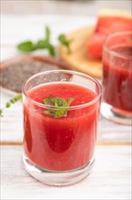 Watermelon juice with chia seeds and mint in glass on a white wooden background with linen textile.