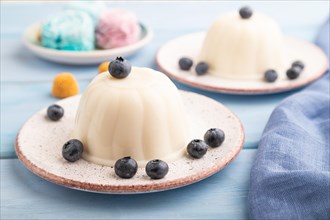 White milk jelly with blueberry on blue wooden background and blue linen textile. side view, close