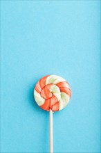 Single lollipop candy on blue pastel background. copy space, top view, flat lay