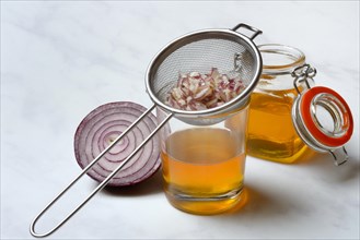 Honey in a jar and chopped onion as ingredients for cough syrup, sieve