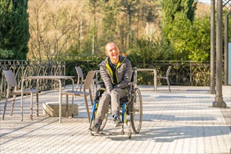 Horizontal photo with wide view and copy space of a disabled man in wheelchair enjoying the sun in